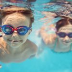 Happy kids swimming underwater in pool